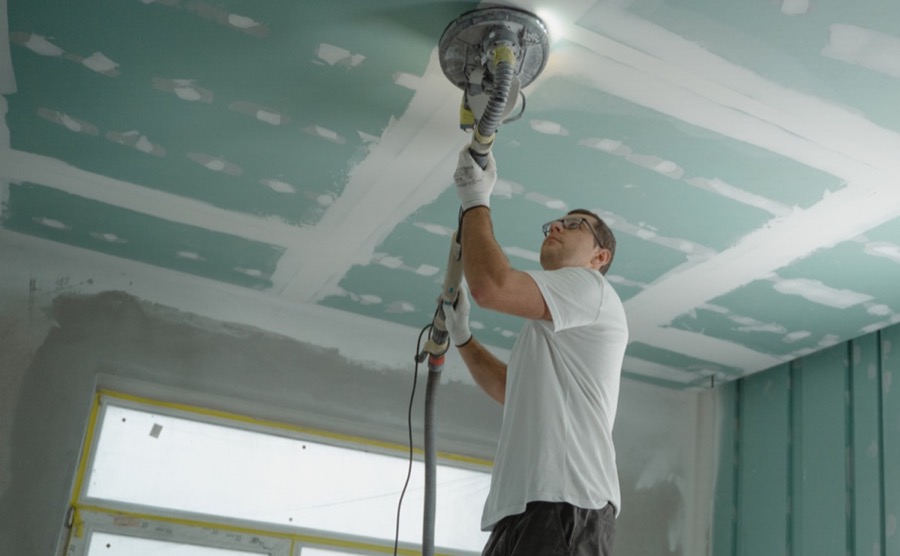 Trabajador lijando plafón durante una remodelación